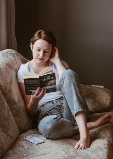 Girl reading a book on her couch